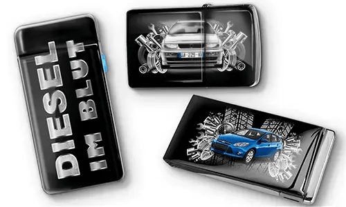 Drei schwarze Feuerzeuge mit Auto-Motiven und metallischen Akzenten. Eines trägt den Text „DIESEL IM BLUT“, die anderen zeigen rote und blaue Autos mit mechanischen Motiven. Ein sportlicher Ton wird vermittelt.