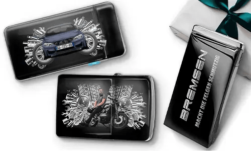 Elegante Geschenkboxen mit einem blauen Auto und einem Biker, umgeben von metallischen Zahnrädern. Eine Box trägt den Text „BREMSEN Macht Die Regeln Schmutzig“, was einen dynamischen, kantigen Ton hinzufügt.