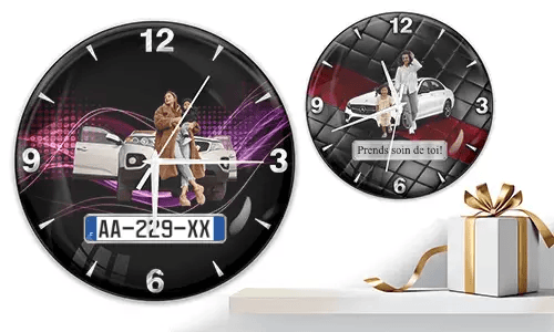 Two wall clocks with family car scenes: left with woman and child at white SUV over purple waves, right with white car and quilted red-black background