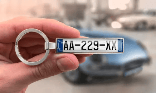 Porte-clés argenté style plaque d’immatriculation avec numéros personnalisés, tenu à la main