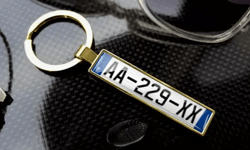 Gold license plate keychain displays engraved text in a polished metal frame