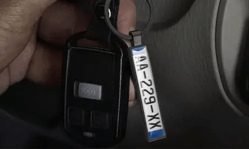 Llavero plateado de placa de matrícula cuelga de las llaves del coche dentro del vehículo