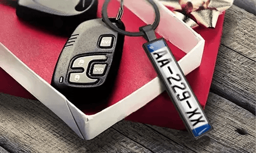 Metal license plate keychain displays engraved numbers beside car keys