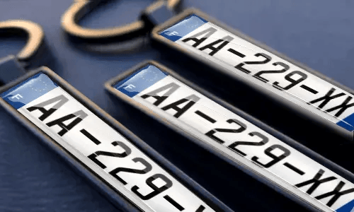 Spersonalizowane breloki z tablicą rejestracyjną pokazują wygrawerowane numery i własny tekst w metalowych ramkach