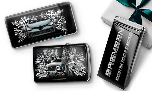 Car-themed wallets featuring sleek cars, checkered flags, and tire patterns on a black background. Beside them, a black gift box with silver text.
