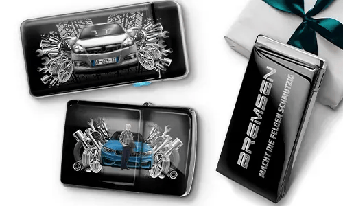 Three automotive-themed items featuring car illustrations and machinery motifs, arranged with a gift box tied with a green ribbon on the side.
