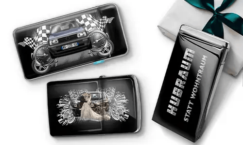 Three black wallets with car-themed designs and checkered flags, set against a white background. One shows a car with wheels, another features a couple, and one has 