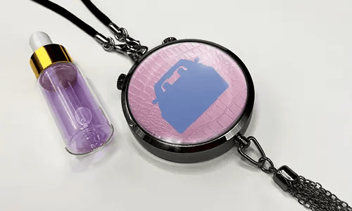 Pendant with pink background and white sports car, next to purple dropper bottle with gold cap