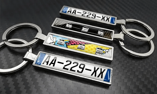 Comic-style license plate keychains arranged on a carbon-textured surface with colorful car graphics