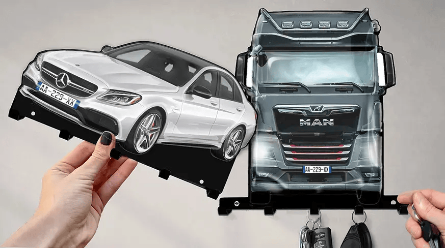 Wandmontierter Schlüsselhalter mit abnehmbaren Formen eines weißen Mercedes-Benz und eines schwarzen MAN-LKWs, jeweils mit Haken für Schlüssel